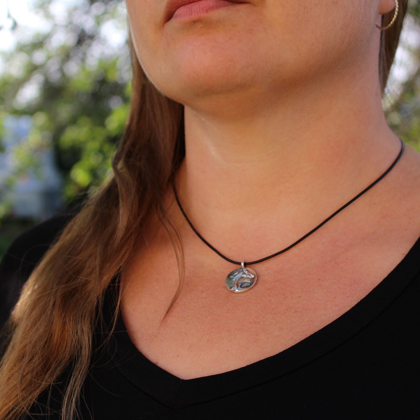 woman wearing silver horse pendant on her neck