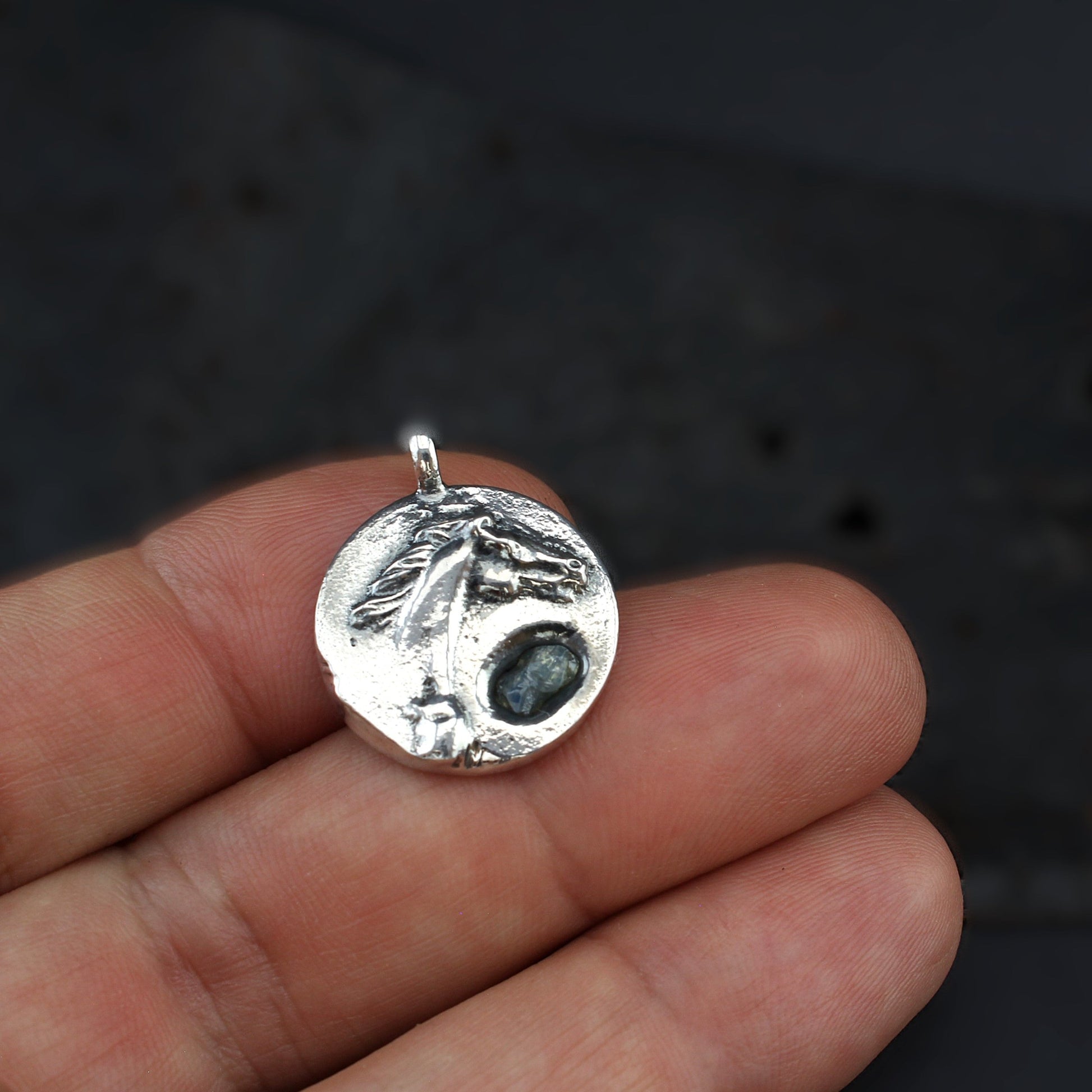 horse silver pendant with rough sapphire front on hand
